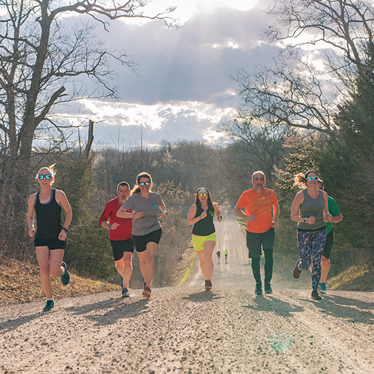 group of people running down dirt road