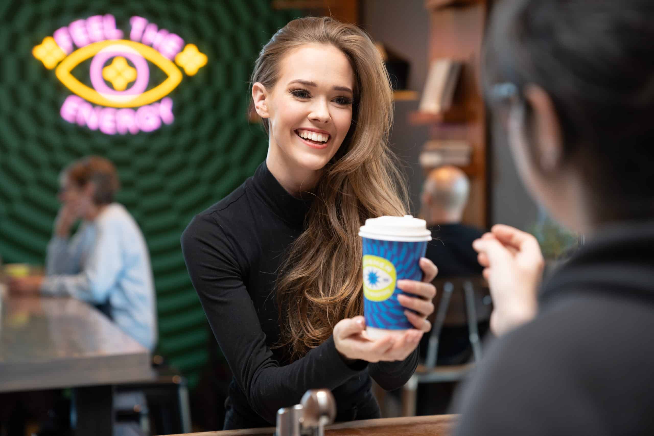 Two models exchanging a cup of coffee at a local coffee shop for Local Advertising and Local Marketing.