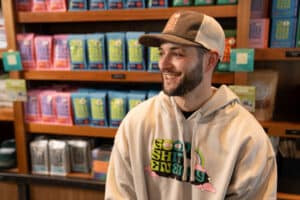 Beaming customer wearing a casual hat and hoodie enjoys the local vibe at a coffee shop, as captured by Drive Social Media's local marketing and local advertising campaign.