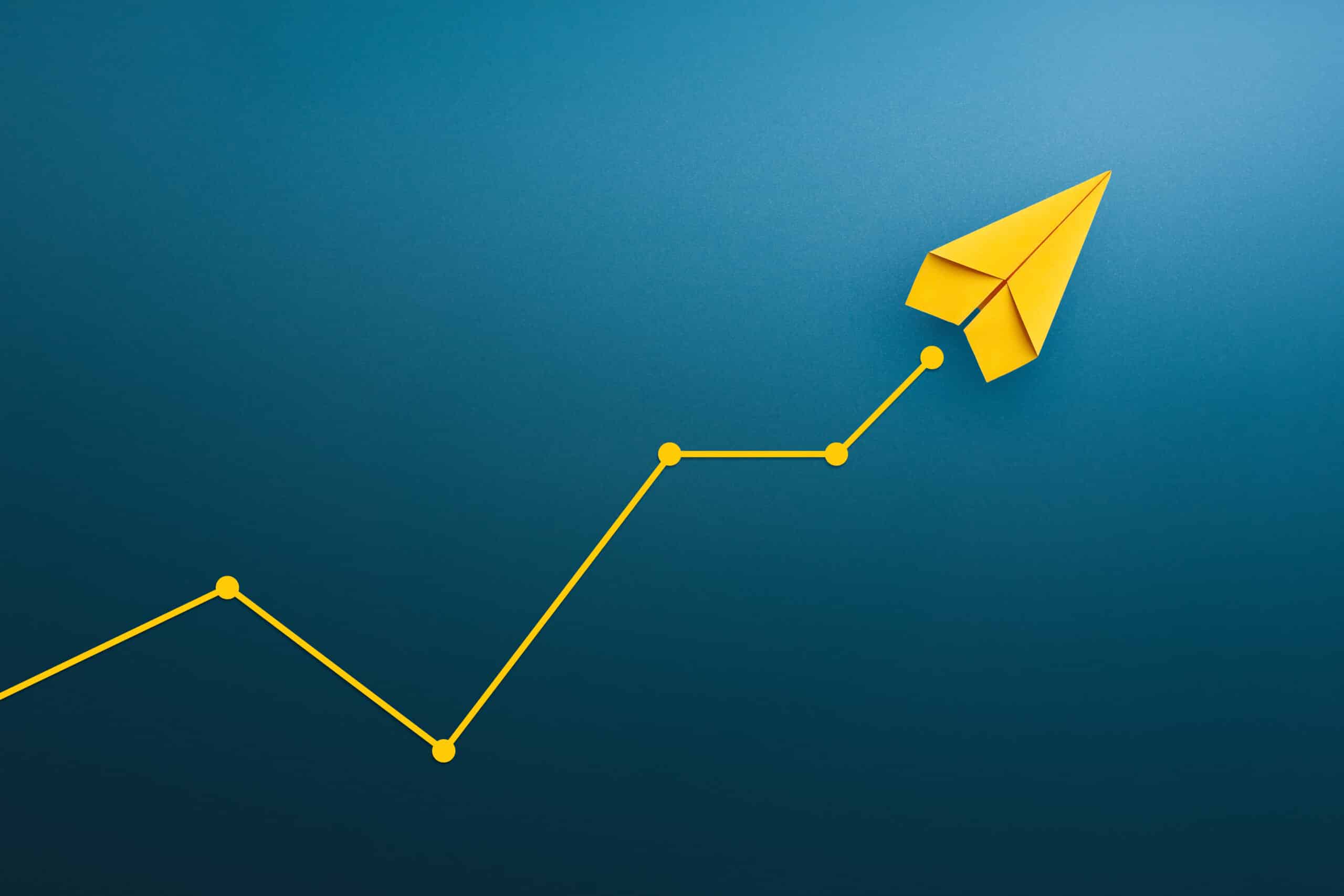 Yellow paper airplane on an upward graph line, representing trends in social media marketing.