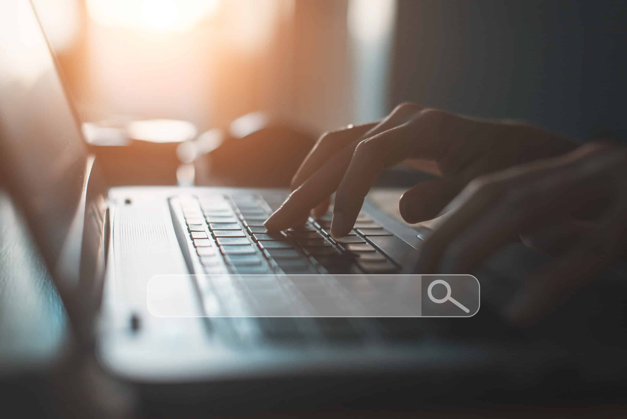 Hands typing on a laptop keyboard with a search bar overlay, representing referral traffic and social media marketing.