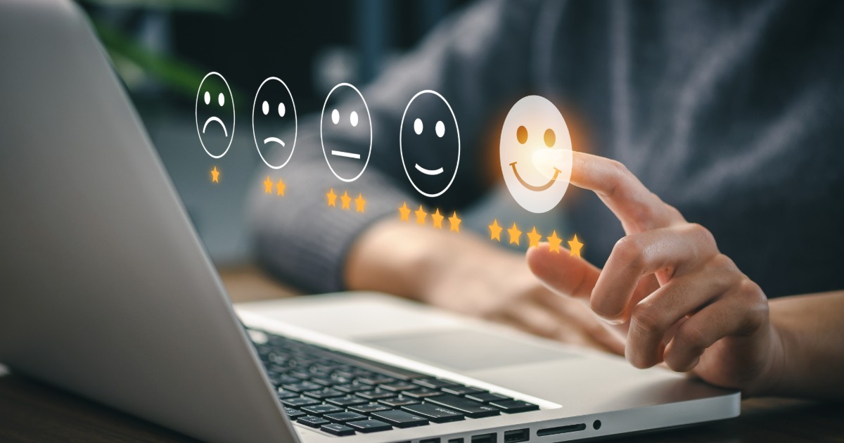 Five rating faces from sad (one star) to happy (five stars) above a laptop, with a finger selecting the happiest face